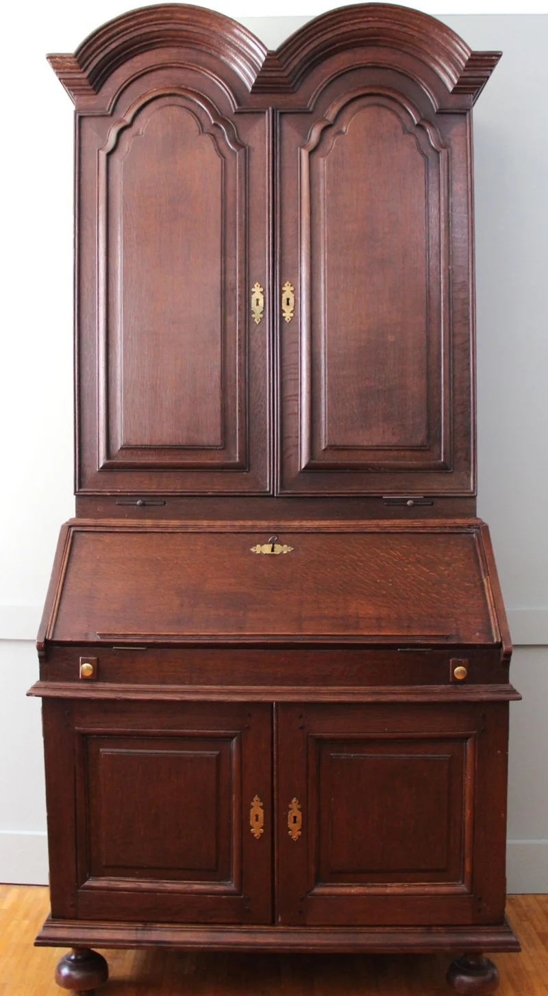 Double dome bureau 18e eeuw - Meubel › Kasten - €1495.00 - Tweeledige eiken bureau met gesloten opbouw. Opgedeeld in vele vakken en met twee uitschuifbare kandelaarhouders tussen onder- en bovendeel.
De "duble dome" verwijst naar het dubbele pediment bovenaan.

94cm breed, 59cm diep aan het bureaugedeelte, 215cm hoog.

Georgean periode, 18e eeuw