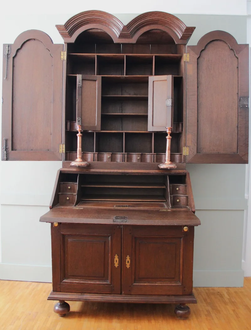 Double dome bureau 18e eeuw - Meubel › Kasten - €1495.00 - Tweeledige eiken bureau met gesloten opbouw. Opgedeeld in vele vakken en met twee uitschuifbare kandelaarhouders tussen onder- en bovendeel.
De "duble dome" verwijst naar het dubbele pediment bovenaan.

94cm breed, 59cm diep aan het bureaugedeelte, 215cm hoog.

Georgean periode, 18e eeuw