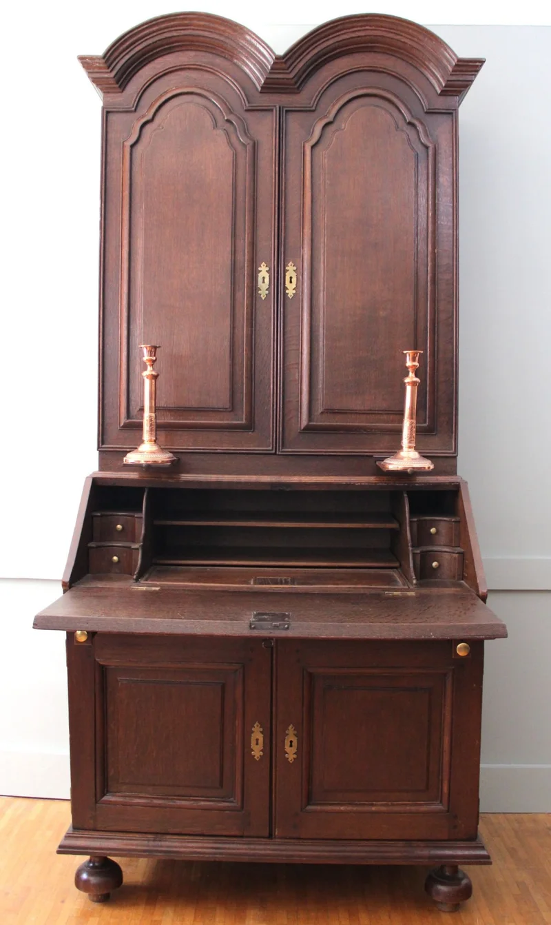 Double dome bureau 18e eeuw - Meubel › Kasten - €1495.00 - Tweeledige eiken bureau met gesloten opbouw. Opgedeeld in vele vakken en met twee uitschuifbare kandelaarhouders tussen onder- en bovendeel.
De "duble dome" verwijst naar het dubbele pediment bovenaan.

94cm breed, 59cm diep aan het bureaugedeelte, 215cm hoog.

Georgean periode, 18e eeuw