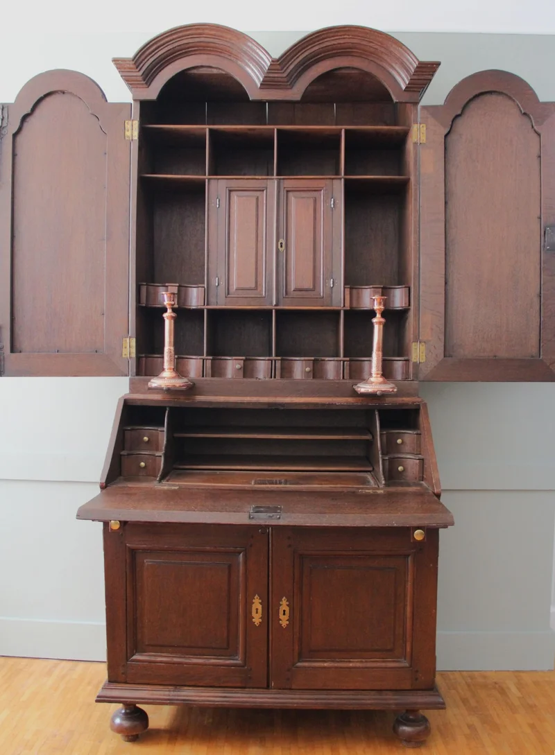 Double dome bureau 18e eeuw - Meubel › Kasten - €1495.00 - Tweeledige eiken bureau met gesloten opbouw. Opgedeeld in vele vakken en met twee uitschuifbare kandelaarhouders tussen onder- en bovendeel.
De "duble dome" verwijst naar het dubbele pediment bovenaan.

94cm breed, 59cm diep aan het bureaugedeelte, 215cm hoog.

Georgean periode, 18e eeuw