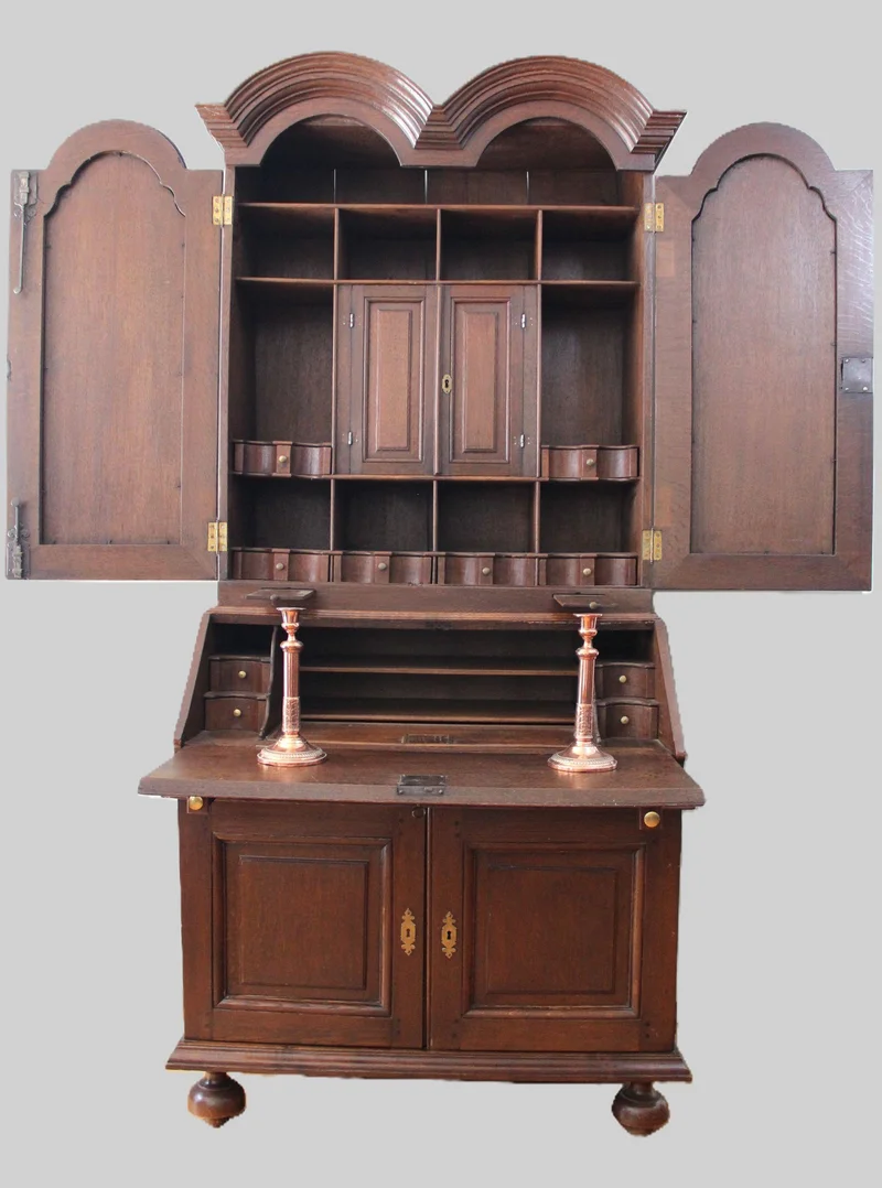 Double dome bureau 18e eeuw - Meubel › Kasten - €1495.00 - Tweeledige eiken bureau met gesloten opbouw. Opgedeeld in vele vakken en met twee uitschuifbare kandelaarhouders tussen onder- en bovendeel.
De "duble dome" verwijst naar het dubbele pediment bovenaan.

94cm breed, 59cm diep aan het bureaugedeelte, 215cm hoog.

Georgean periode, 18e eeuw