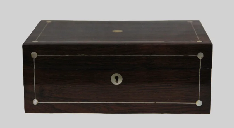 Palissander naaidoos - Diversen › Dozen en kistjes - €150.00 - Naaidoos met oorspronkelijke binnenverdeling in twee lagen. Palissander hout met zilver filet en parelmoer ingelegd op deksel en voorkant.
25 x 17cm, 10cm hoog.
Georgean tijdperk, ca 1820