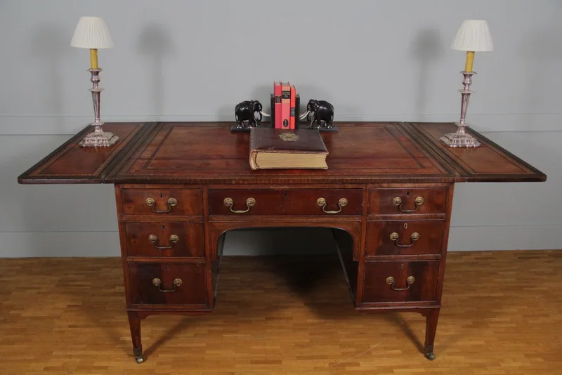 Regency partnerdesk - Meubel › Tafels - €1500.00 - Mahoniehouten partnerdesk met aan de ene zijde 6 laden en aan de andere zijde 3 laden en twee kastjes.
Opklapbare bladen aan beide zijden.
Origineel leder met goudrand indruk.
91cm diep, 119cm breed, opklapbaar tot 183cm, 75cm hoog.

Regency periode, ca 1820