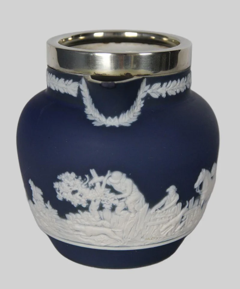 Roomkan met Wedgewood motief (2) - Porselein › Serviesgoed - Roomkan met decoratie in de stijl van Wedgewood en een verzilverde kraag.
Kleine schilfer van de schenktuit.
Gemerkt: Tunstall England, Adam
12cm hoog
19e eeuw